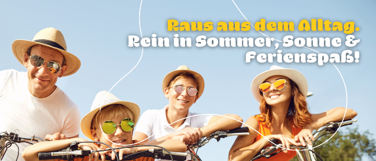 Eine vierköpfige Familie, bestehend aus zwei Erwachsenen und zwei Kindern, fährt mit Hüten und Sonnenbrillen Fahrrad, lächelt und posiert für ein Foto vor einem blauen Himmel.