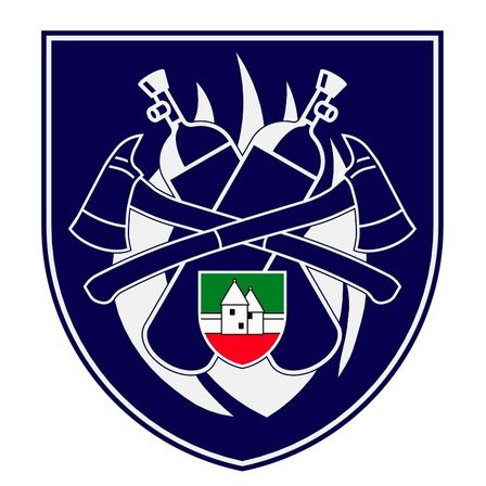 Ein blauer Schild mit gekreuzten Äxten und Feuerlöschern, in der Mitte ein Hauswappen mit roten, weißen und grünen Farben.