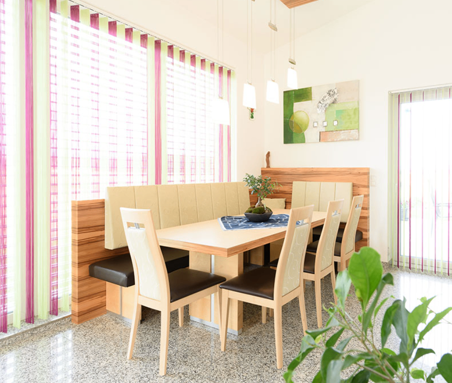 Essbereich mit Holztisch und Stühlen, einer grünen Pflanze und einem Gemälde an der Wand.
