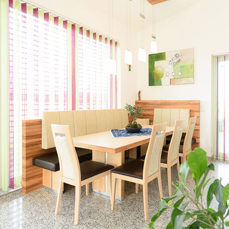 Essbereich mit Holztisch und Stühlen, einer grünen Pflanze und einem Gemälde an der Wand.