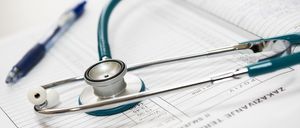 Ein Stethoskop liegt auf einem medizinischen Dokument mit Patientendaten, einschließlich Name, Adresse und Telefonnummer. Ein Stift befindet sich in der Nähe.