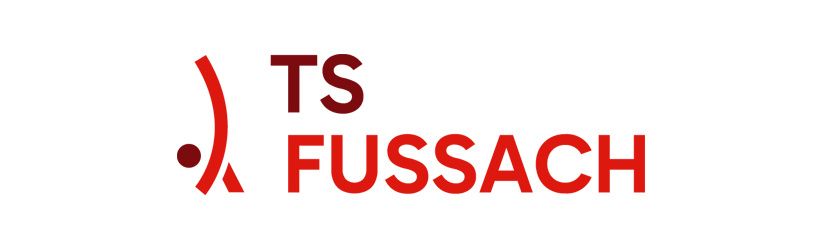 Das Logo von TS Fussach ist auf weißem Hintergrund dargestellt. Es zeigt roten Text mit einem einzigartigen roten Symbol.