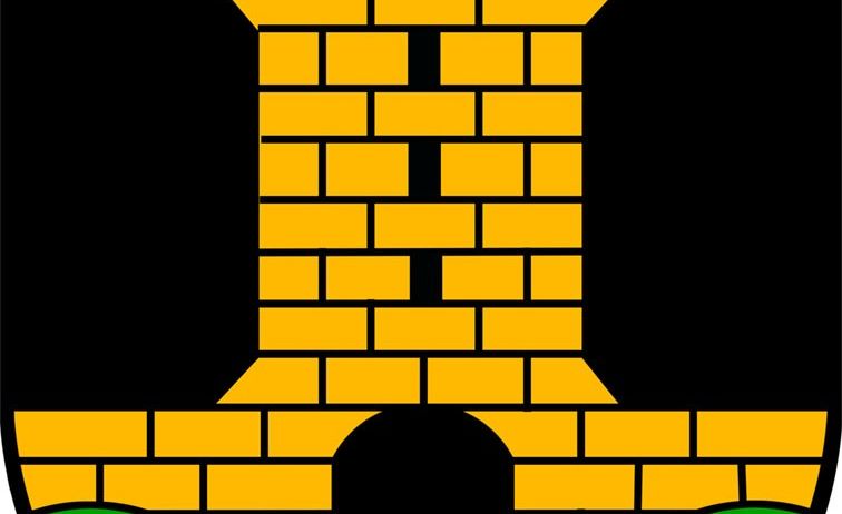 Ein schwarzer Schild mit einem gelben Ziegelturm, der einen schwarzen Bogeneingang und zwei grüne blattartige Formen auf beiden Seiten aufweist.