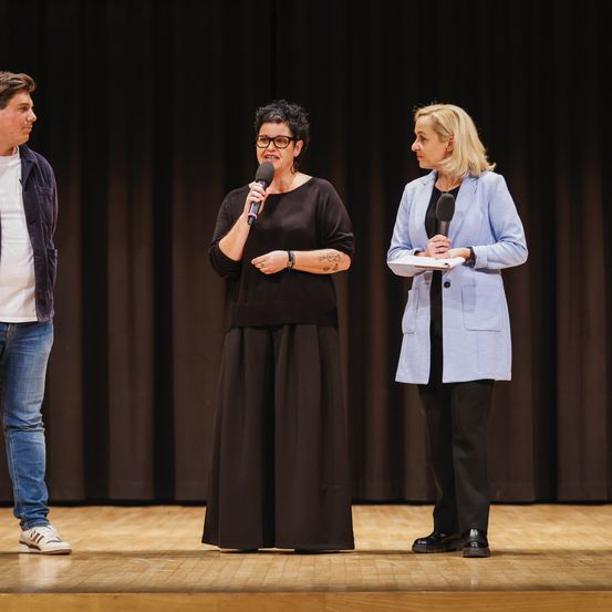 Bild enthält, Stage, Coat, Adult, Male, Man, Person, Jeans, Jacket, Shoe, Microphone