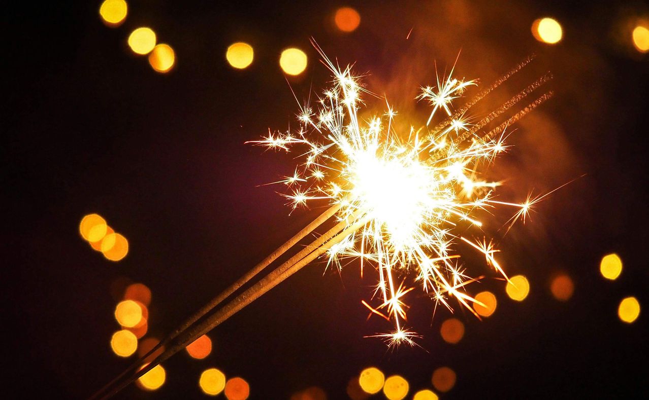 Eine Nahaufnahme eines brennenden Feuerwerks mit hellem Licht am Ende und Funken, die sich gegen einen dunklen Hintergrund ausbreiten.