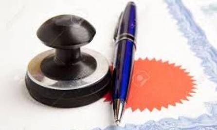 A blue pen and a black stamp sit on top of a document with a blue and orange border.