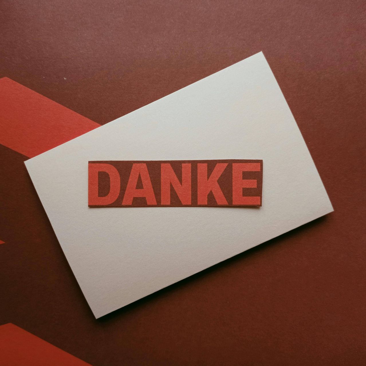 A white envelope with a red sticker displaying the word Danke on a red background.