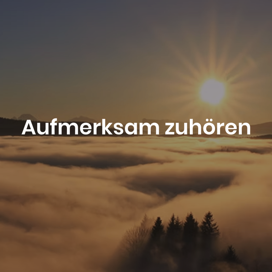 A bright sun rises above a sea of clouds, casting a warm glow on the landscape. Trees silhouetted in the foreground stand amidst the fog. The words 'Aufmerksam zuhören' appear in white at the top.