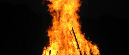 Ein Lagerfeuer brennt nachts hell und wirft ein warmes Licht, das die umliegende Dunkelheit erhellt.