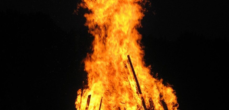 Ein Lagerfeuer brennt nachts hell und wirft ein warmes Licht, das die umliegende Dunkelheit erhellt.