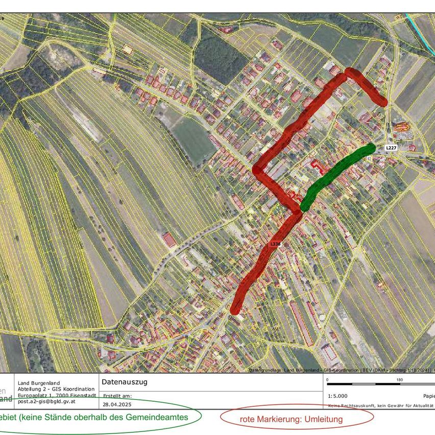 An aerial view of a map showing a village with red and green lines indicating a proposed road. The map includes data sources, the date of creation, and a scale. The village is surrounded by farmland.