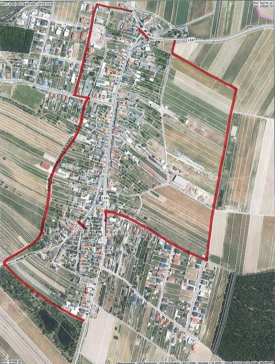 An aerial view of a town with a grid-like road layout. Red lines highlight specific areas, possibly indicating a planned development or area of interest.