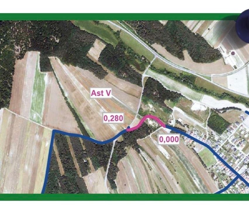 Luftaufnahme einer ländlichen Landschaft mit einem markierten Pfad, der mit 'Ast V' beschriftet ist, und Entfernungsmarkierungen 0,280 und 0,000. Die Landschaft umfasst Felder, Bäume und eine Straße.