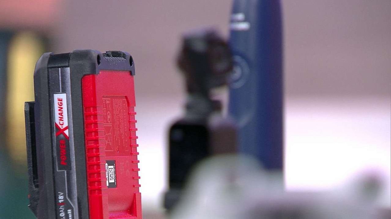 A close-up of a red electronic device with a barcode, next to a blurry blue and black object.