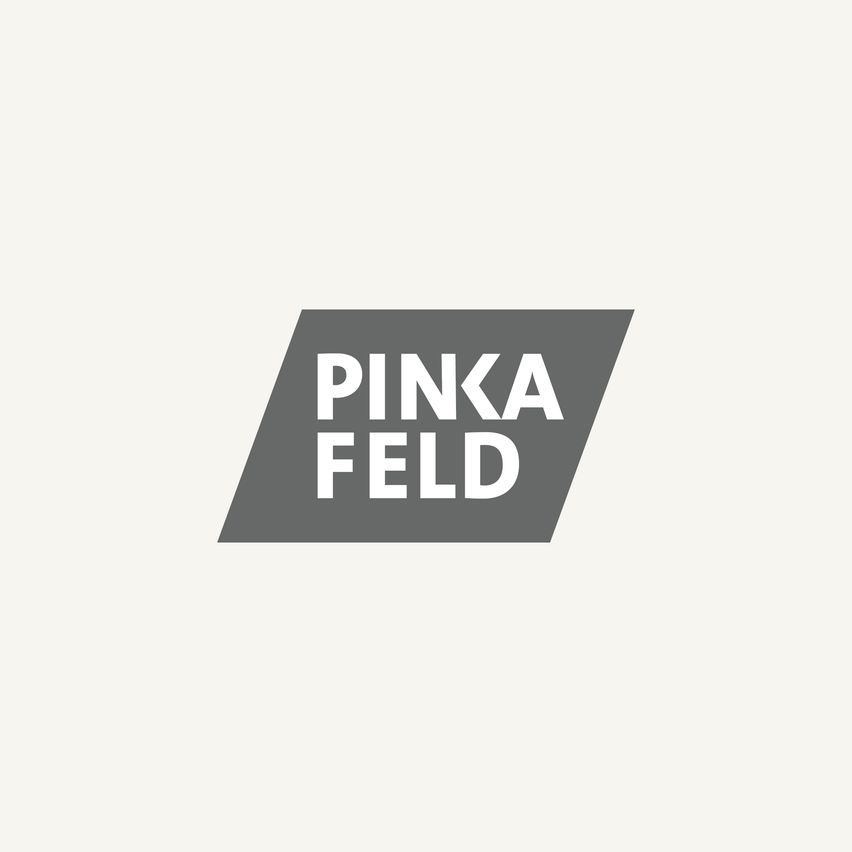 Ein graues Quadrat enthält das Wort 'PINKA' in weißer Schrift über dem Wort 'FELD', ebenfalls in weißer Schrift. Das Bild hat einen schlichten, hellgrauen Hintergrund.