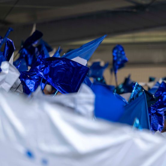 Eine Nahaufnahme verschiedener blauer und weißer Papierdekorationen, möglicherweise von einer Feier oder einem Event, verstreut auf einer weißen Oberfläche.