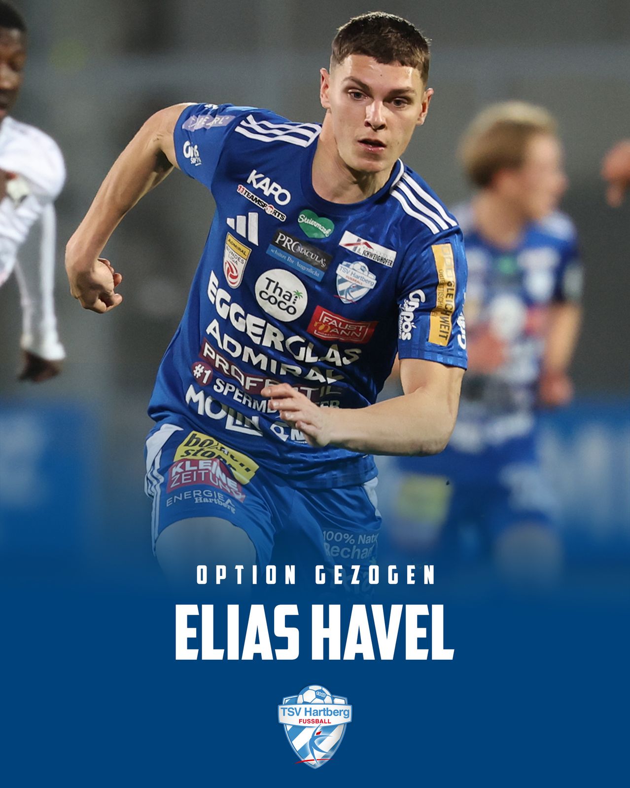 Ein Fußballspieler läuft auf dem Feld und trägt ein blaues Trikot mit verschiedenen Logos. Hinter ihm läuft ein weiterer Spieler in Weiß. Das Bild hat einen blauen Hintergrund und den Text 'Option Gezogen Elias Havel'.