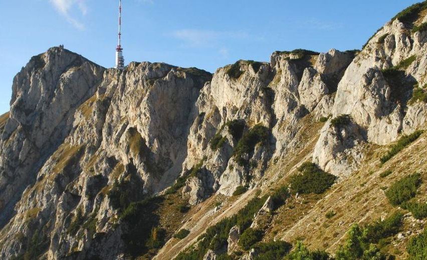 Ein Blick auf einen felsigen Berg mit einem hohen Turm auf der Spitze und einem klaren blauen Himmel im Hintergrund.