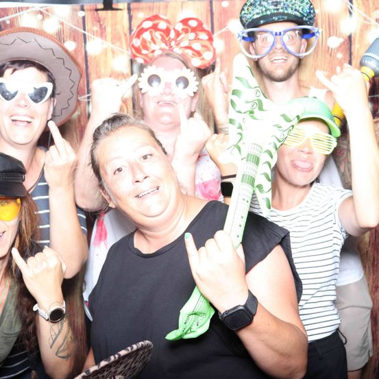 Eine Gruppe von Menschen mit verschiedenen Hüten und Sonnenbrillen, die für ein Foto mit einer grünen Gitarre in der Mitte posiert.
