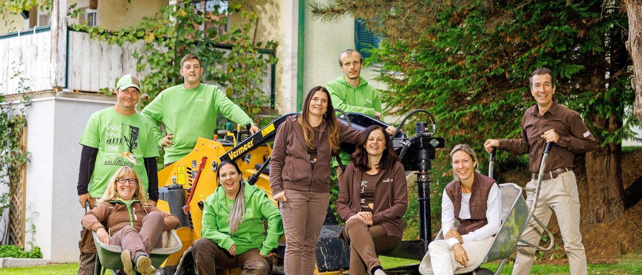 Eine Gruppe von Personen in grünen Shirts und braunen Hosen posiert für ein Foto mit einem Vermeer-Traktor im Hintergrund.