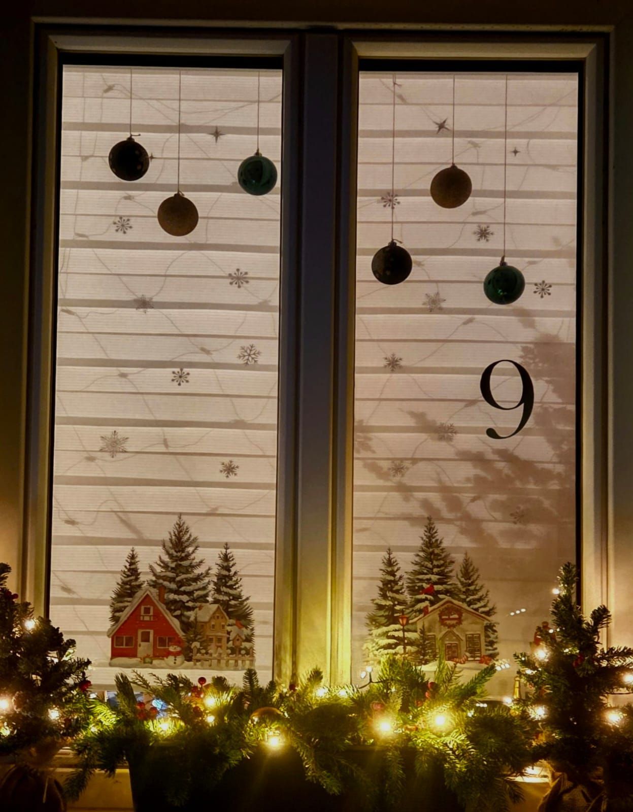 The window displays Christmas ornaments and snowflakes, with a Christmas tree on the sill and a house scene on the blinds. The date '9' is prominently shown.