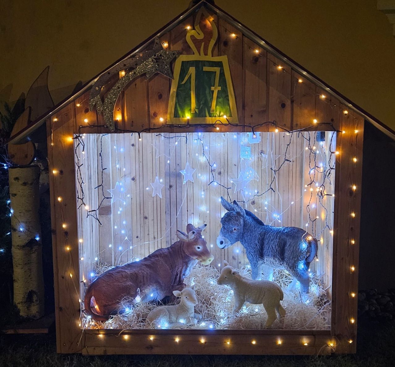 Eine Holzschachtel mit der Nummer 17 oben drauf. Im Inneren der Box sind Weihnachtslichter, Krippenfiguren und Heu. Die Tiere sind ein Esel, eine Kuh und zwei Lämmer.