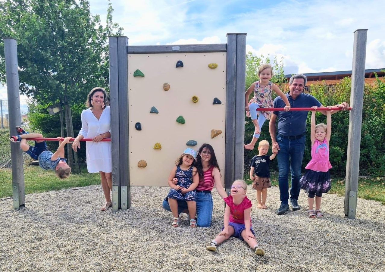 Eine Familie posiert für ein Foto vor einer Kletterwand im Park.