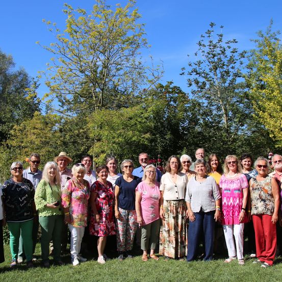 Eine Gruppe von Menschen, wahrscheinlich eine Familie, steht auf einem Grasfeld vor Bäumen. Sie lächeln alle für ein Foto.