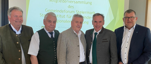 Fünf Männer stehen vor einer Präsentationsfolie mit grünem Hintergrund und weißer Schrift, die Herzlich Willkommen zur ordentlichen Mitgliederversammlung des Gemeindeforum Steiermark besagt.