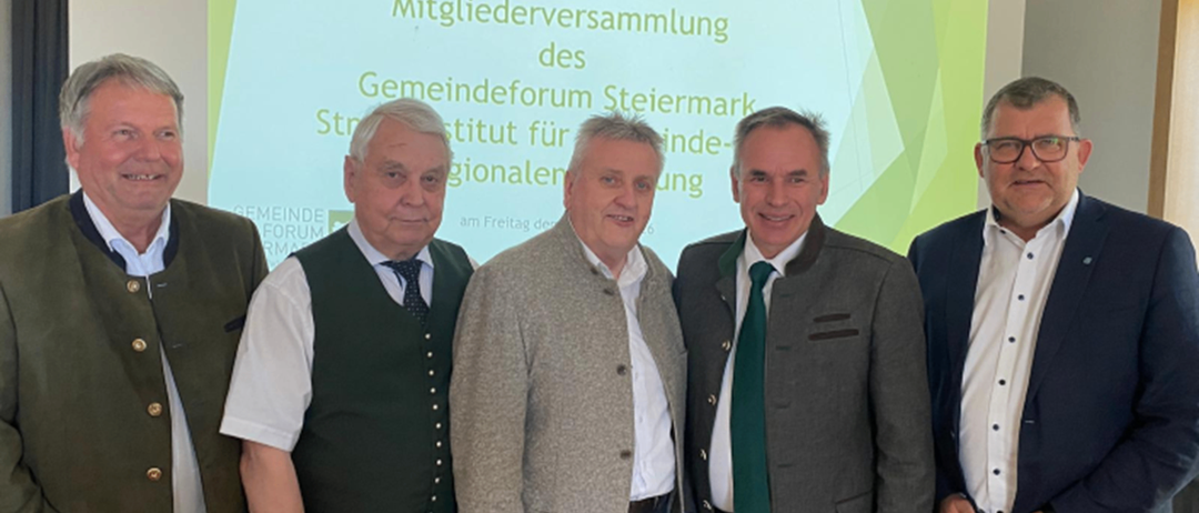 Fünf Männer stehen vor einer Präsentationsfolie mit grünem Hintergrund und weißer Schrift, die Herzlich Willkommen zur ordentlichen Mitgliederversammlung des Gemeindeforum Steiermark besagt.