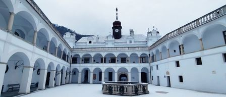 Ein Bild eines weißen Gebäudes mit Bögen und einem verschneiten Uhrturm.