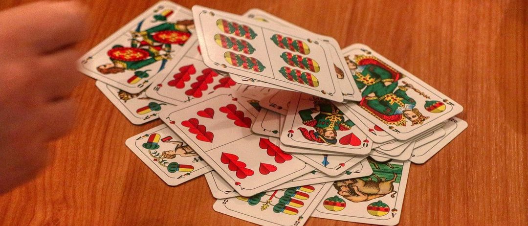 Ein Stapel verschiedener Spielkarten mit roten und grünen Farben liegt auf einem Holztisch.