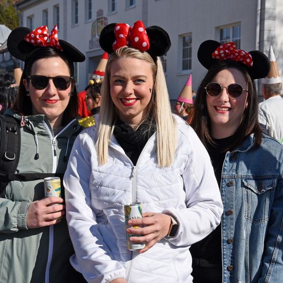 Drei Frauen mit Minnie-Maus-Ohren, in Winterkleidung, lächeln und posieren für ein Foto.
