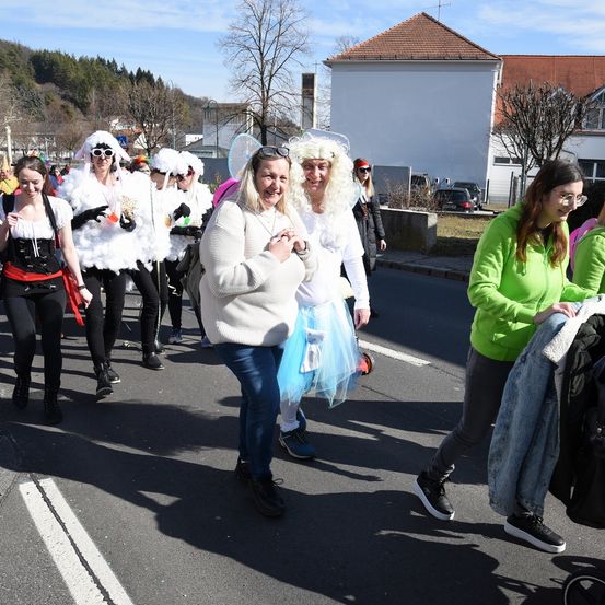 Menschen gehen tagsüber auf der Straße. Einige tragen Kostüme, andere nicht.