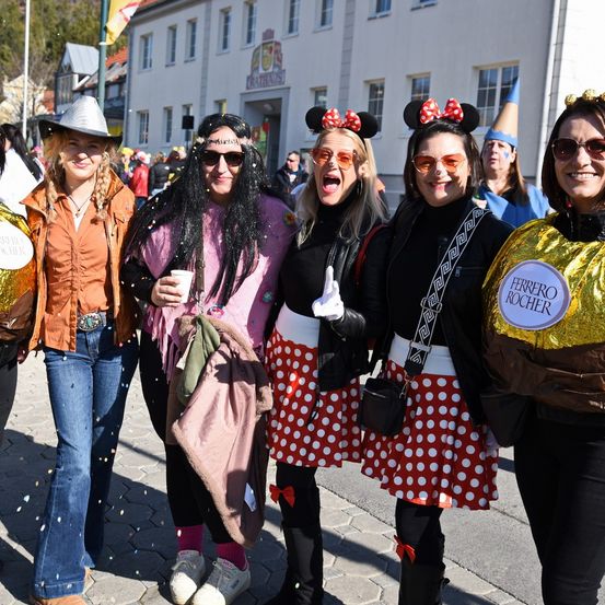 Fünf Frauen in Kostümen posieren vor einem Gebäude für ein Foto.