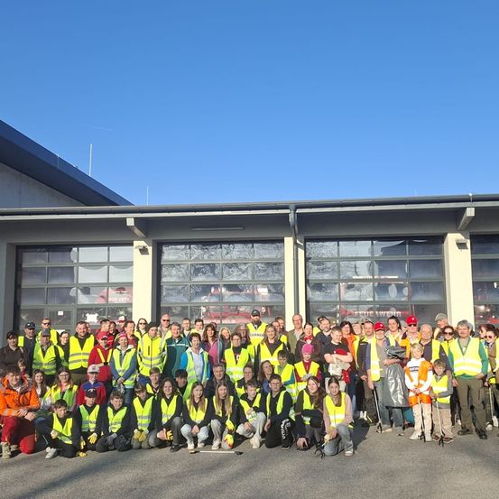 Eine Gruppe von Menschen in neongrünen Westen posiert für ein Foto vor einem Gebäude.