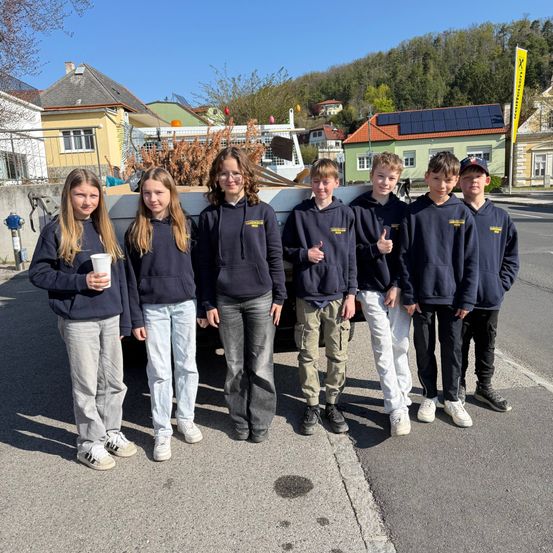 Eine Gruppe von Kindern posiert für ein Foto vor einem Fahrzeug mit einem voll beladenen Pickup-Bett mit Materialien.
