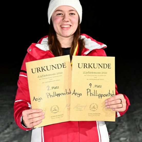 Eine lächelnde Frau in einer roten Jacke und einer weißen Mütze hält zwei Urkunden in den Händen, eine mit Platz 2 und die andere mit Platz 9. Beide Urkunden sind mit Urkunde beschriftet und auf das Jahr 2020 datiert.