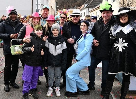 Eine Gruppe von Erwachsenen und Kindern in Kostümen posiert für ein Foto auf einer Straße während einer Veranstaltung.