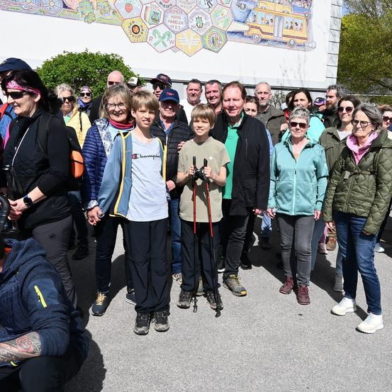 Eine Gruppe von Erwachsenen und Kindern steht vor einem Gebäude, einige halten Wanderstöcke. Sie scheinen für ein Foto zu posieren.