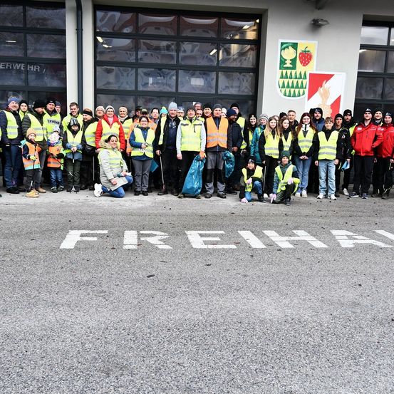 Eine Gruppe von Freiwilligen in Warnwesten versammelt sich vor einem Gebäude mit 'FREIHA' auf dem Boden geschrieben.