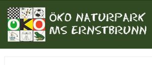 Eine grüne Tafel zeigt weißen Text, der 'Zu Naturpark Ernstbrunn' in Fettdruck schreibt. Darunter befindet sich ein weißer Rand.