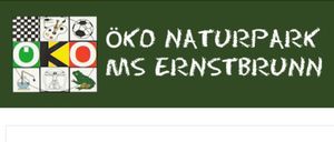 Eine grüne Tafel zeigt weißen Text, der 'O Naturpark S Ernstbrunn' lautet. Darunter steht das Wort 'Verein' in Weiß auf weißem Hintergrund.