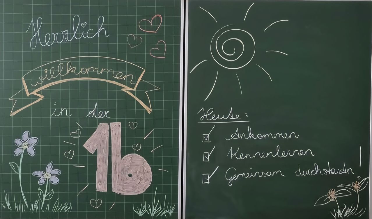 Ein Tafel mit einer Spiralsonne und einer Liste von abgehakten Punkten, einschließlich 'Ankommen', 'Kennenlernen' und 'Gemeinsam'. Ein anderes Tafel hat einen herzförmigen Banner, die Zahl 16 und das Wort 'lieb'.