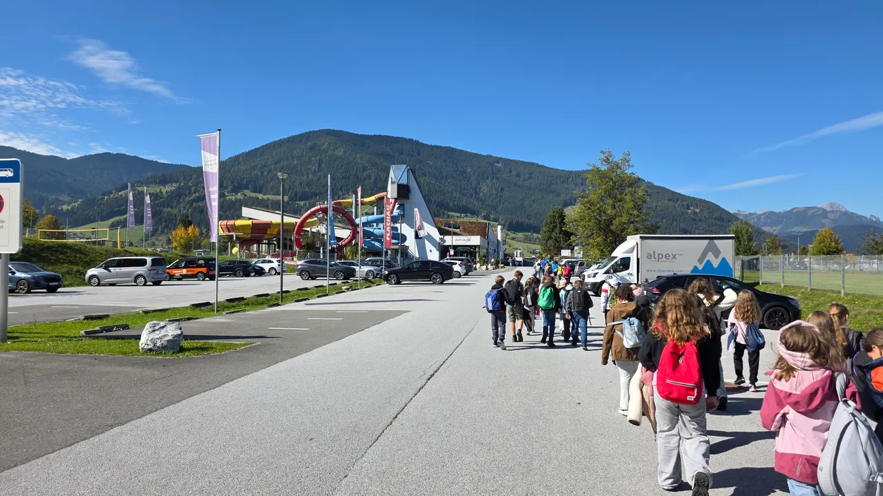 Eine Gruppe von Menschen geht auf einer Straße vor einem Wasserpark.