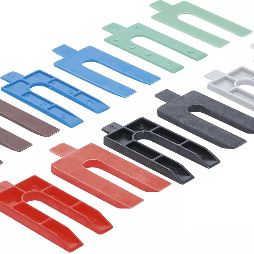 Eine Sammlung von U-förmigen Kunststoffklammern in verschiedenen Farben, einschließlich Blau, Grün, Braun, Rot, Schwarz und Weiß, auf weißem Hintergrund dargestellt.