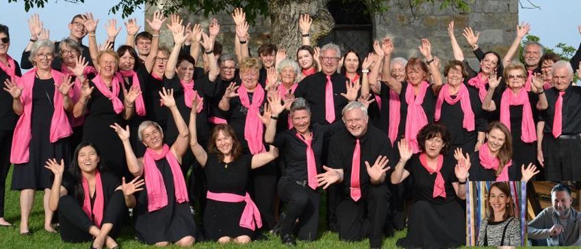 Eine Gruppe Erwachsener in schwarzer und rosa Kleidung, einschließlich Schals und Krawatten, posiert für ein Foto im Freien bei sonnigem Wetter.