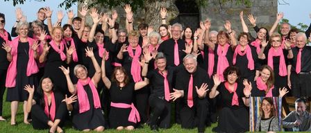 Eine Gruppe Erwachsener in schwarzer und rosa Kleidung, einschließlich Schals und Krawatten, posiert für ein Foto im Freien bei sonnigem Wetter.