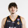 Ein Basketballspieler mit lockigem Haar trägt ein Panthers-Trikot mit der Nummer 4 und posiert für ein Foto.