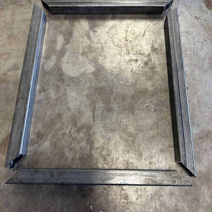 Ein quadratischer Rahmen aus Metallstangen auf einem Betonboden. Der Rahmen ist oben offen.